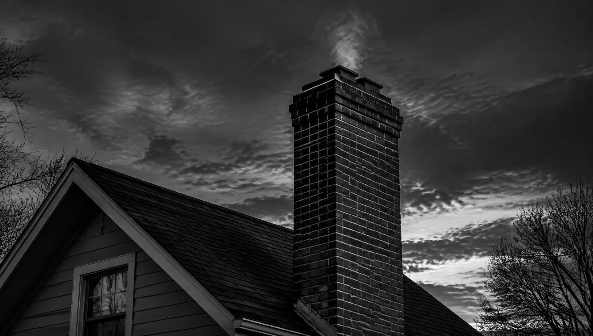 Brick residential chimney against a dramatic evening sky